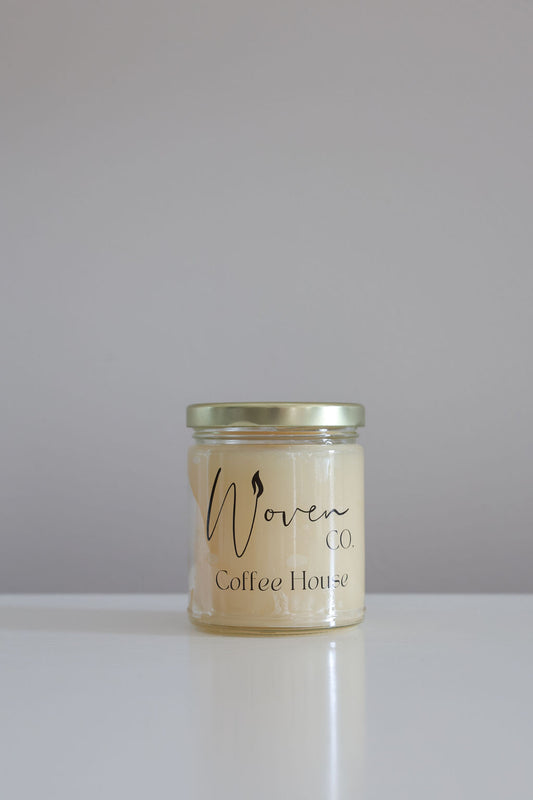 Jar of coffee house candle with a label on a white surface and gray background