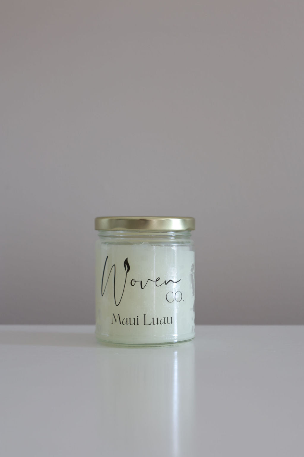 Candle jar with a label on a plain background