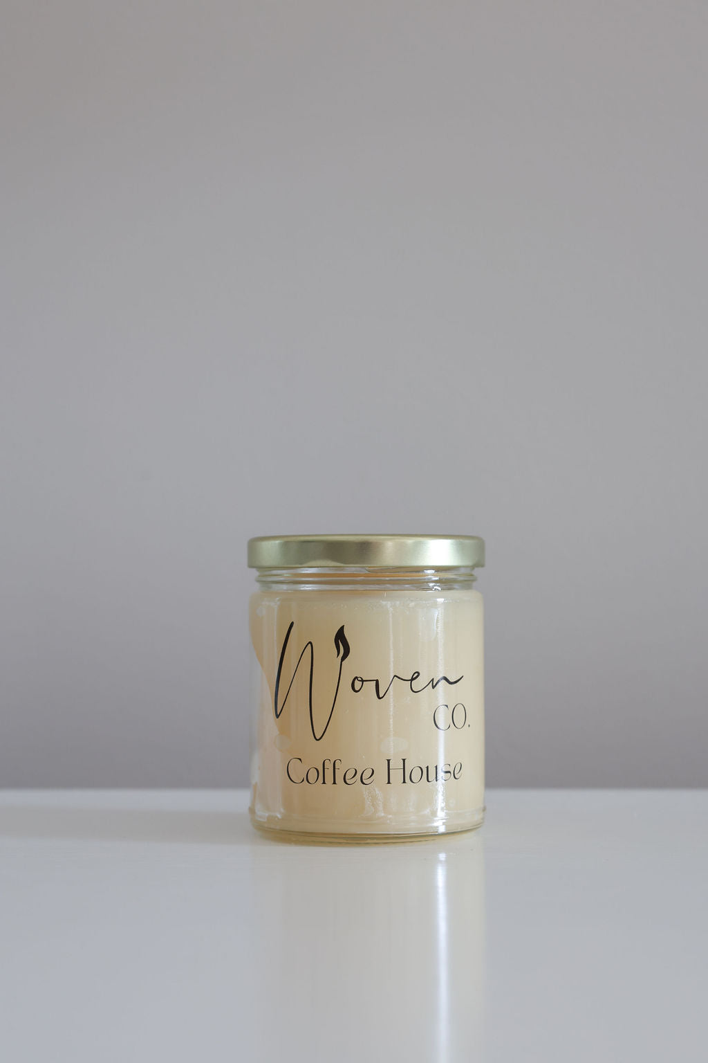 Jar of coffee house candle with a label on a white surface and gray background