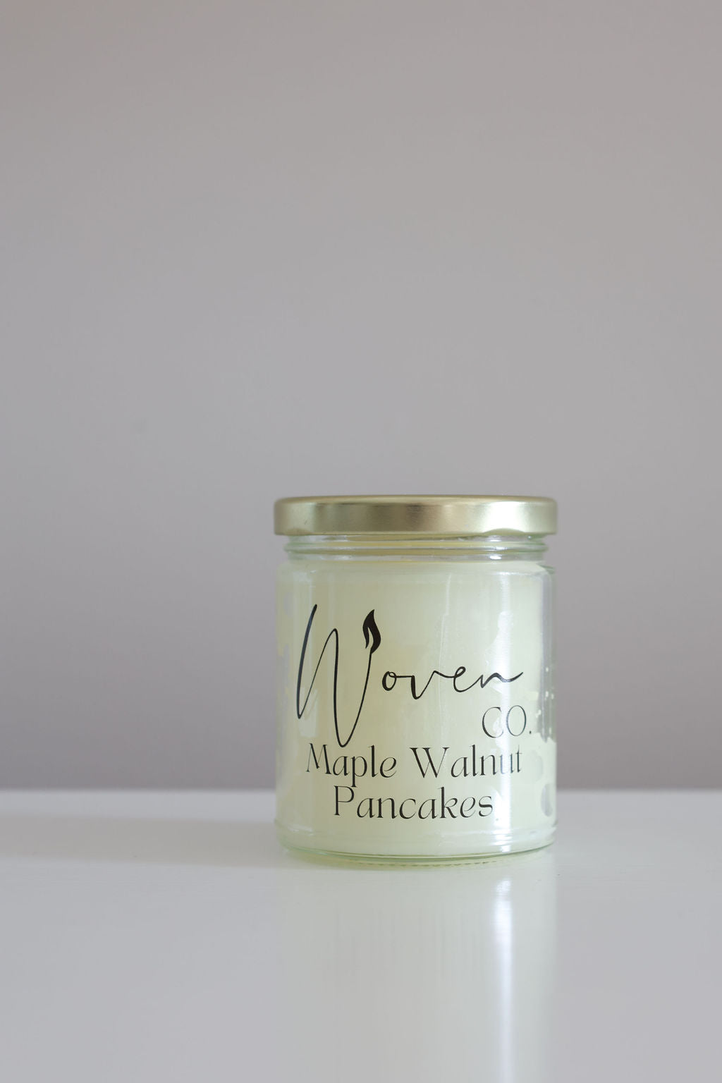 Jar of 'Maple Walnut Pancakes' by Woven Co. on a white surface with a gray background